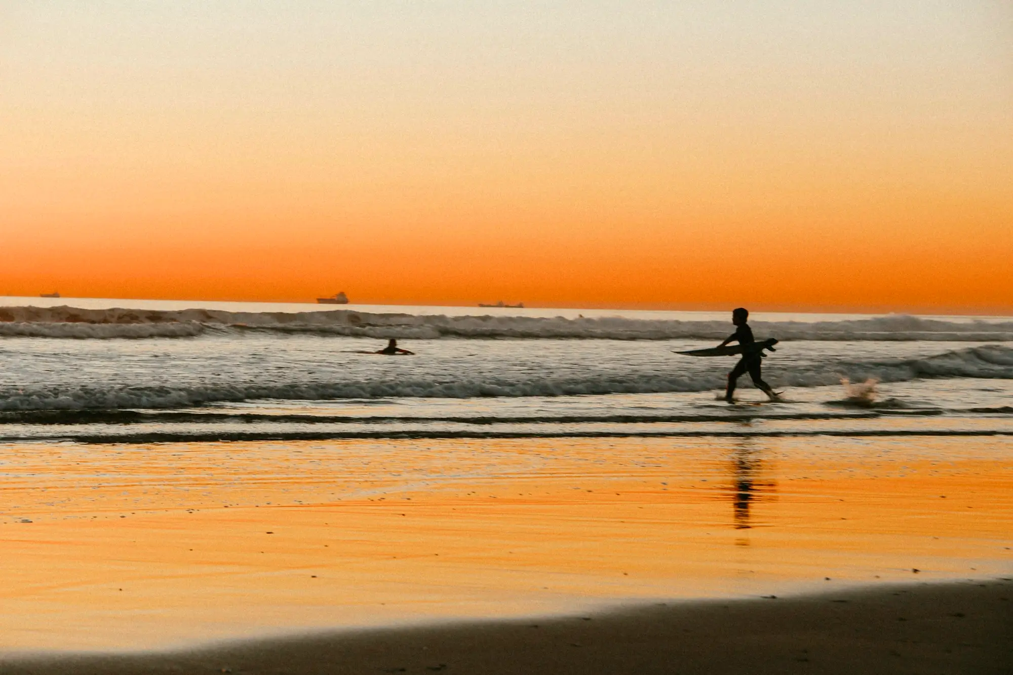 Un surfeur au coucher du soleil sur la plage de Carcavelos